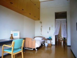 木製家具と採光が特徴の居室。ベッド・椅子・収納が配置されている。