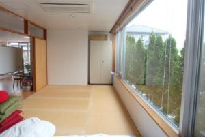 大きな窓からの眺望が特徴の広々とした居室。木製の内装で温かみがある。