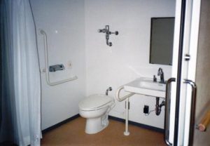 介護対応の浴室。手すり付きの洗面台とトイレが配置された浴室空間。